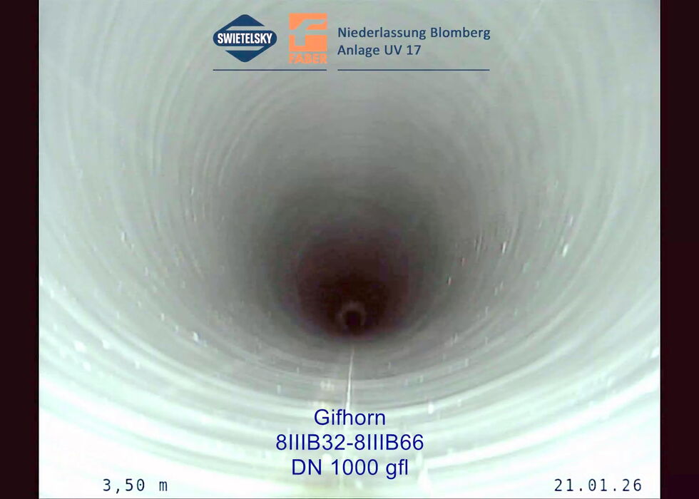 Looking down the inside of a large white pipe with a dark center and inspection markings.