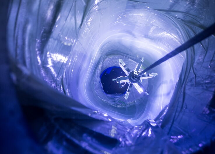 An inside view of underwater exploration equipment with a focus on the robotic arm and surrounding blue light.