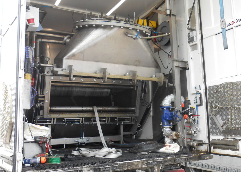 Interior of a service truck fitted with large industrial cleaning machinery and hoses.