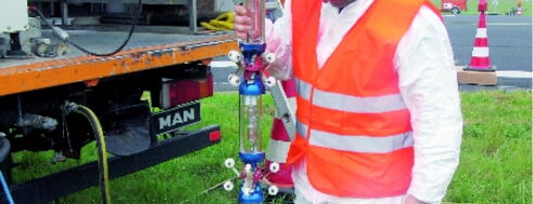 A field technician in safety gear is checking a vertical equipment setup, ensuring safe and efficient operations.