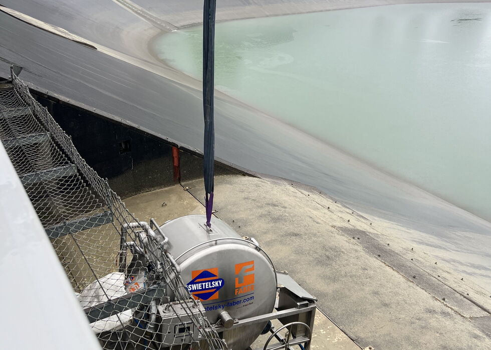 Crane lifting a pump or equipment unit beside a drained pool during liner repair.