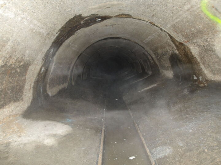 Dark tunnel interior with a narrow rail track running through the center.