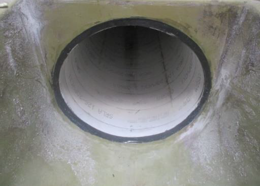 Circular concrete pipe opening set into a rough wall surface.