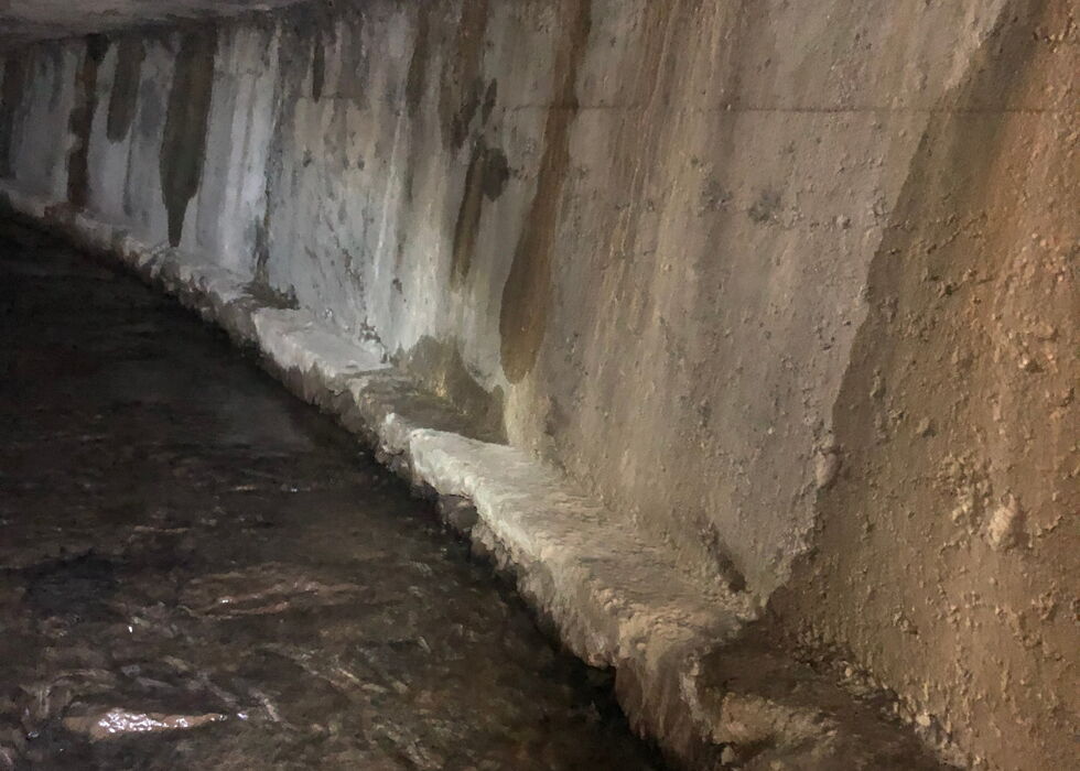 Curved concrete underground water channel with flowing clear water inside