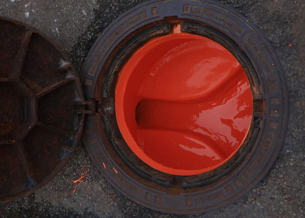 A circular industrial valve with vivid red liquid inside.