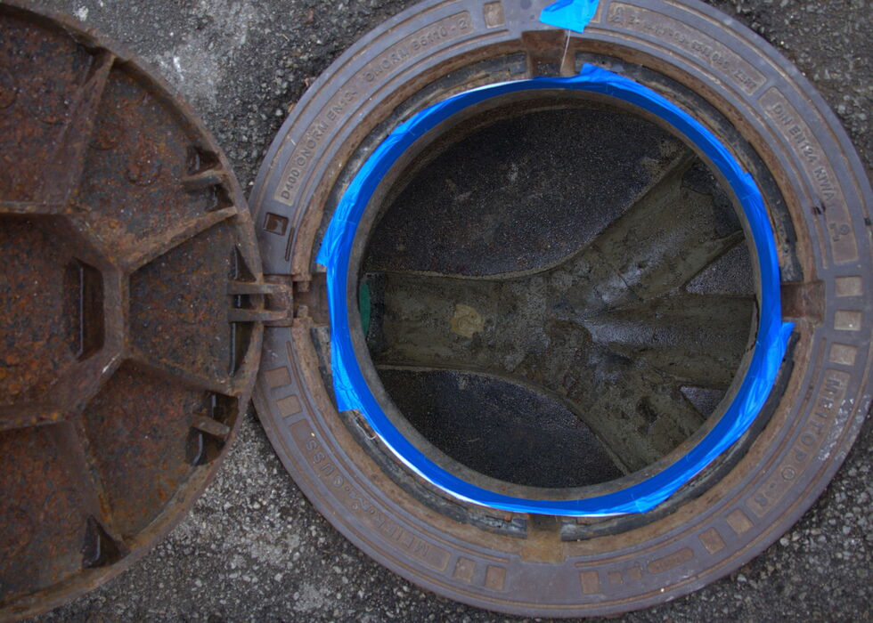 Top-down view of a circular manhole cover with a glowing blue ring on the ground.